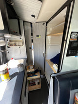 RV rental interior featuring a compact kitchen, pull-out storage, and a stand-up shower for comfortable mobile living.