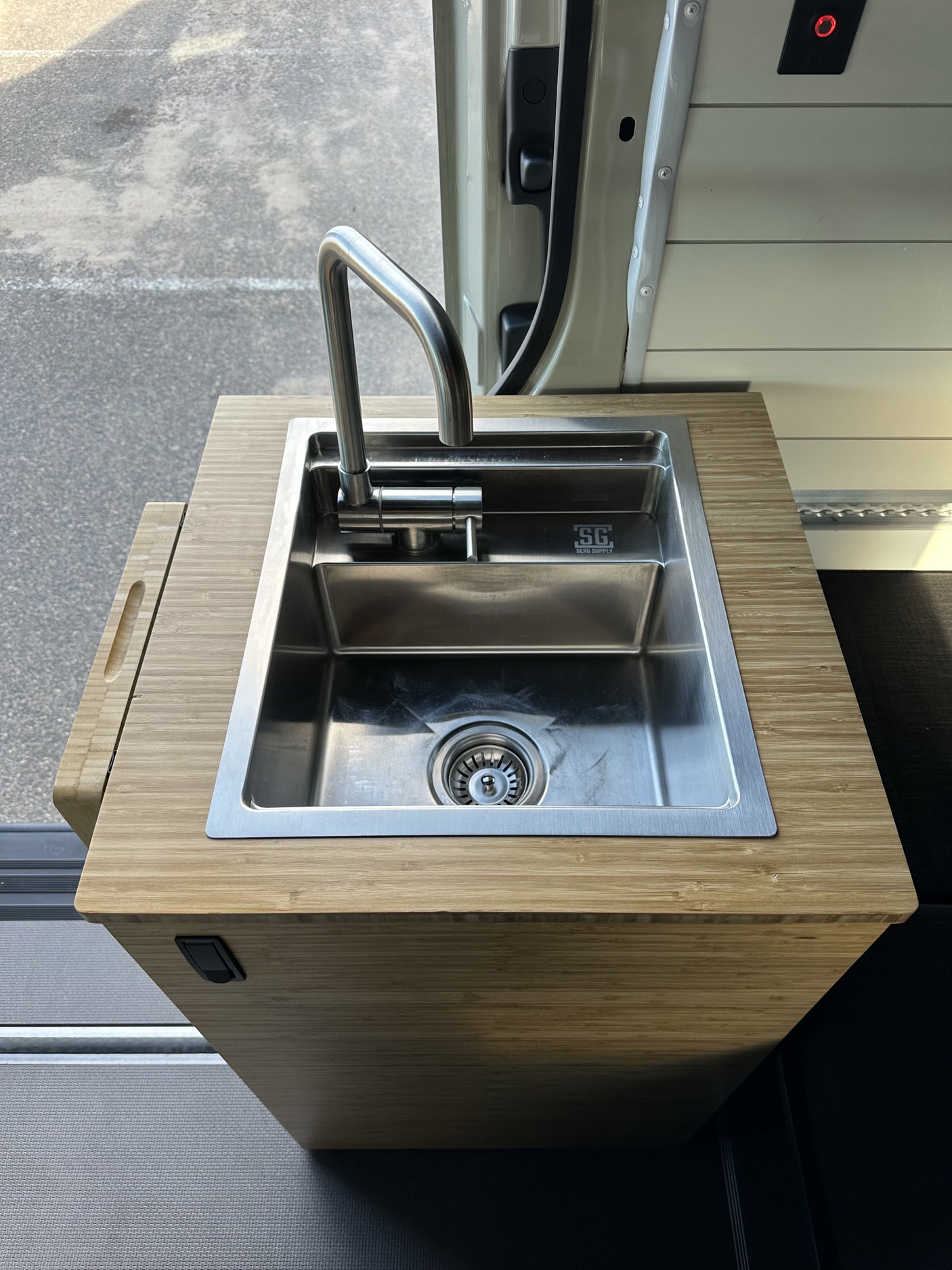 Functional RV rental kitchen with a sleek stainless steel sink, pull-down faucet, and bamboo counter.