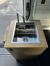 Functional RV rental kitchen with a sleek stainless steel sink, pull-down faucet, and bamboo counter.