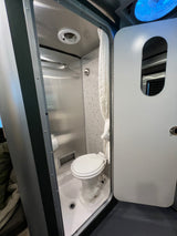 Inside this compact RV rental, a clever flip-up lid reveals a self-contained bathroom with a toilet and shower.