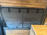 Dark grey quilted window covers in an RV rental van, with wood accents and countertop, for comfort & privacy.
