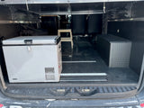 RV rental camper van interior featuring a portable fridge on rails, ample storage, and flexible seating.