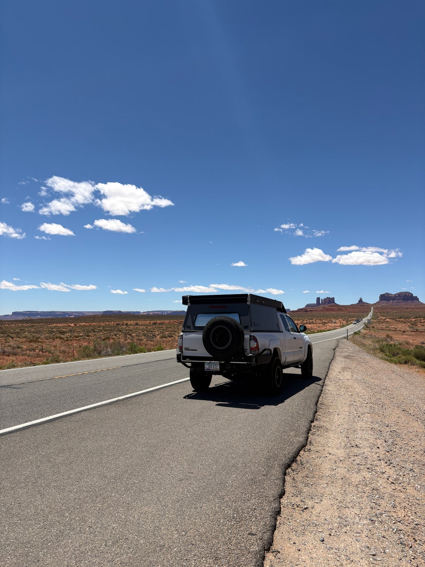 Exploring Monument Valley with an RV rental pickup truck camper on a winding desert road under blue skies. — photo 6