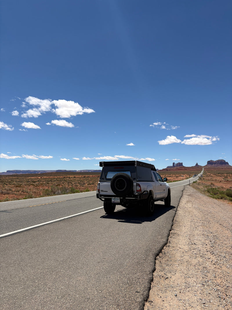 Exploring Monument Valley with an RV rental pickup truck camper on a winding desert road under blue skies. — photo 6