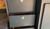 Inside this RV rental, grey storage drawers with push-button latches offer organization. Two are slightly open, revealing wood.