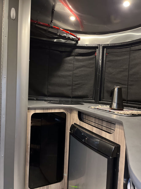 RV rental interior: A compact kitchen with a sink, fridge, coffee pot, and smart hanging storage solution.