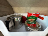 Coffee supplies, including a percolator and Melitta filters, are neatly organized in a bin inside an RV rental.