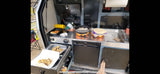 Preparing breakfast in a convenient RV rental outdoor kitchen setup, featuring a portable stove, sink, and fridge.