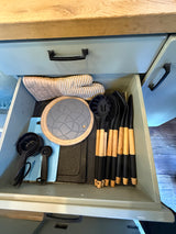 Organized kitchen drawer in an RV rental, featuring oven mitts, measuring cups, and cooking utensils for your adventures.