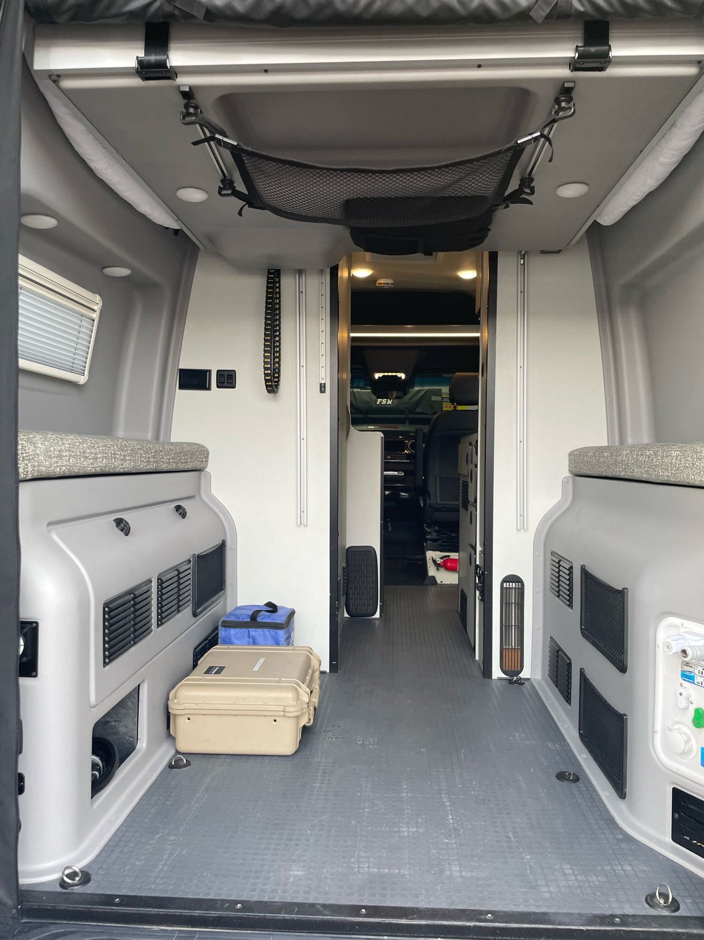 Inside an RV rental camper van: compact interior with built-in storage, versatile seating, and overhead mesh netting for your journey.