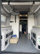Inside an RV rental camper van: compact interior with built-in storage, versatile seating, and overhead mesh netting for your journey.