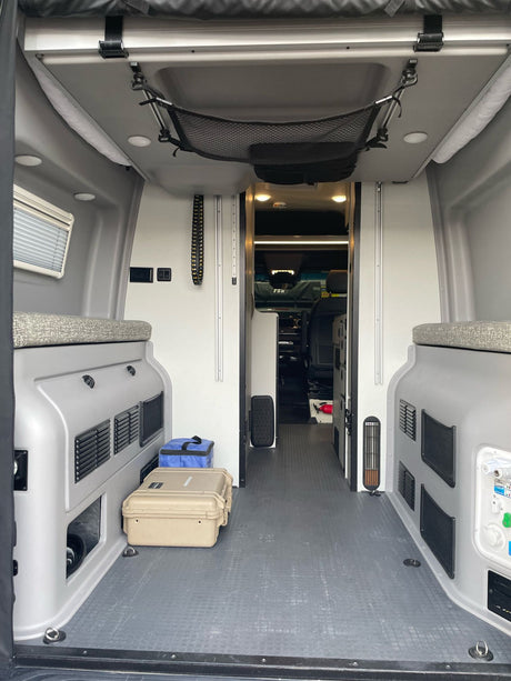 Inside an RV rental camper van: compact interior with built-in storage, versatile seating, and overhead mesh netting for your journey.