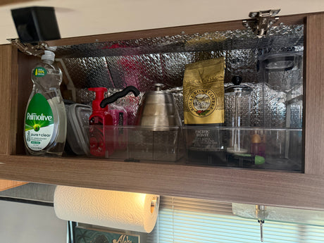 RV rental kitchen cabinet, neatly organized with coffee supplies, dish soap, and insulated lining for travel.