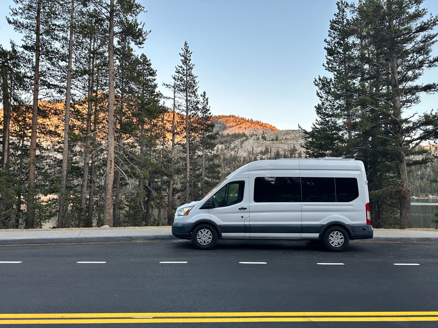  framed by tall pines.|Cozy RV rental interior with a bed — photo 3