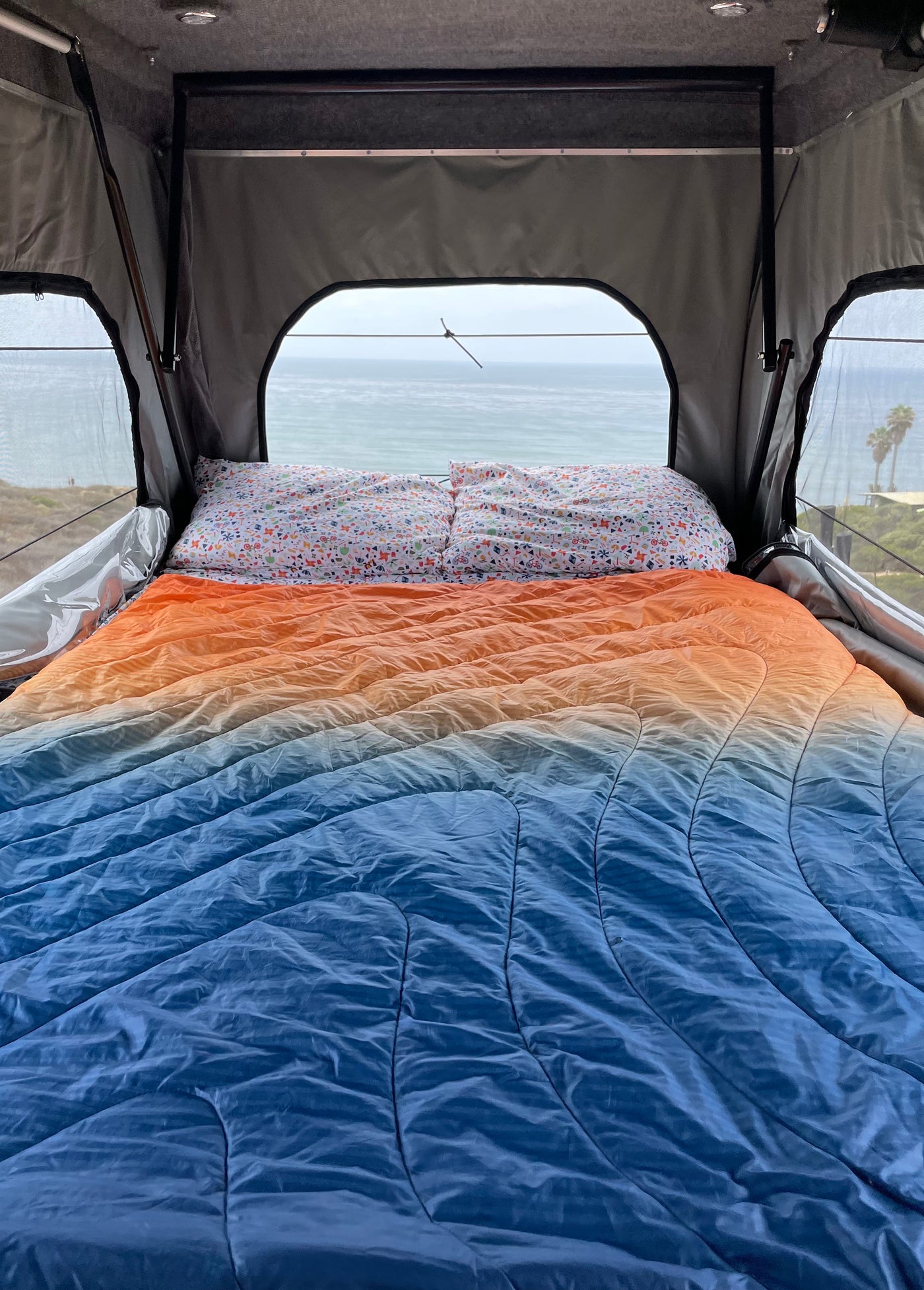 Scenic ocean view from a cozy rv rental bed with an orange & blue comforter. Ideal for relaxing camping trips. — photo 5