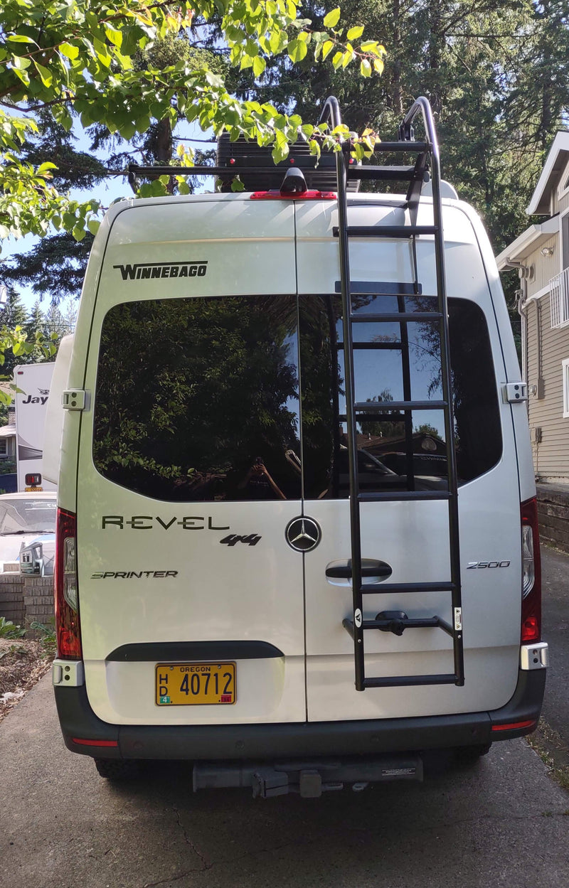 Rear view of a silver Winnebago Revel 4x4 Sprinter van, equipped with a roof rack and ladder, ideal for RV rental. — photo 7