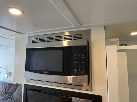 A High Pointe stainless steel microwave oven, mounted in an rv rental. It features a digital control panel and is situated under ceiling lighting.