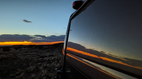 Golden hour captured! An RV rental reflects a vibrant sunset over a wide, grassy desert landscape. Your next adventure awaits.