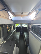 Experience a versatile rv rental camper van interior: pop-top bed, kitchen, fridge, and facing bench seats.