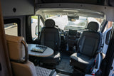 This RV rental interior features swiveling front seats, a table with a chessboard, and a functional cockpit, ready for adventure.