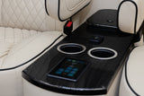 Luxury RV rental interior: cream quilted leather seating, central console with cup holders, USB charger, and touchscreen controls.