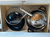 Neatly organized pots, pans, and lids in a compact wooden RV rental compartment. Essential kitchenware.