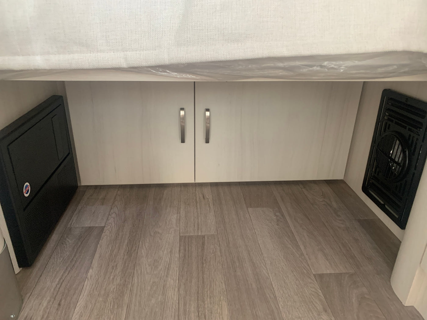 RV rental interior view: power distribution panel, storage cabinets, and an air vent on wood-look flooring. — photo 7