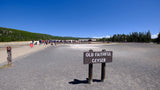 The "OLD FAITHFUL GEYSER" sign stands before a large crowd gathered in Yellowstone National Park. Plan your rv rental trip!