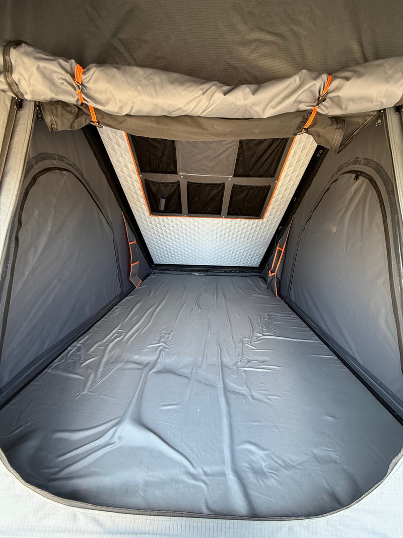Interior view of an RV rental rooftop tent, featuring a grey sleeping area, quilted ceiling, and storage pockets. — photo 7