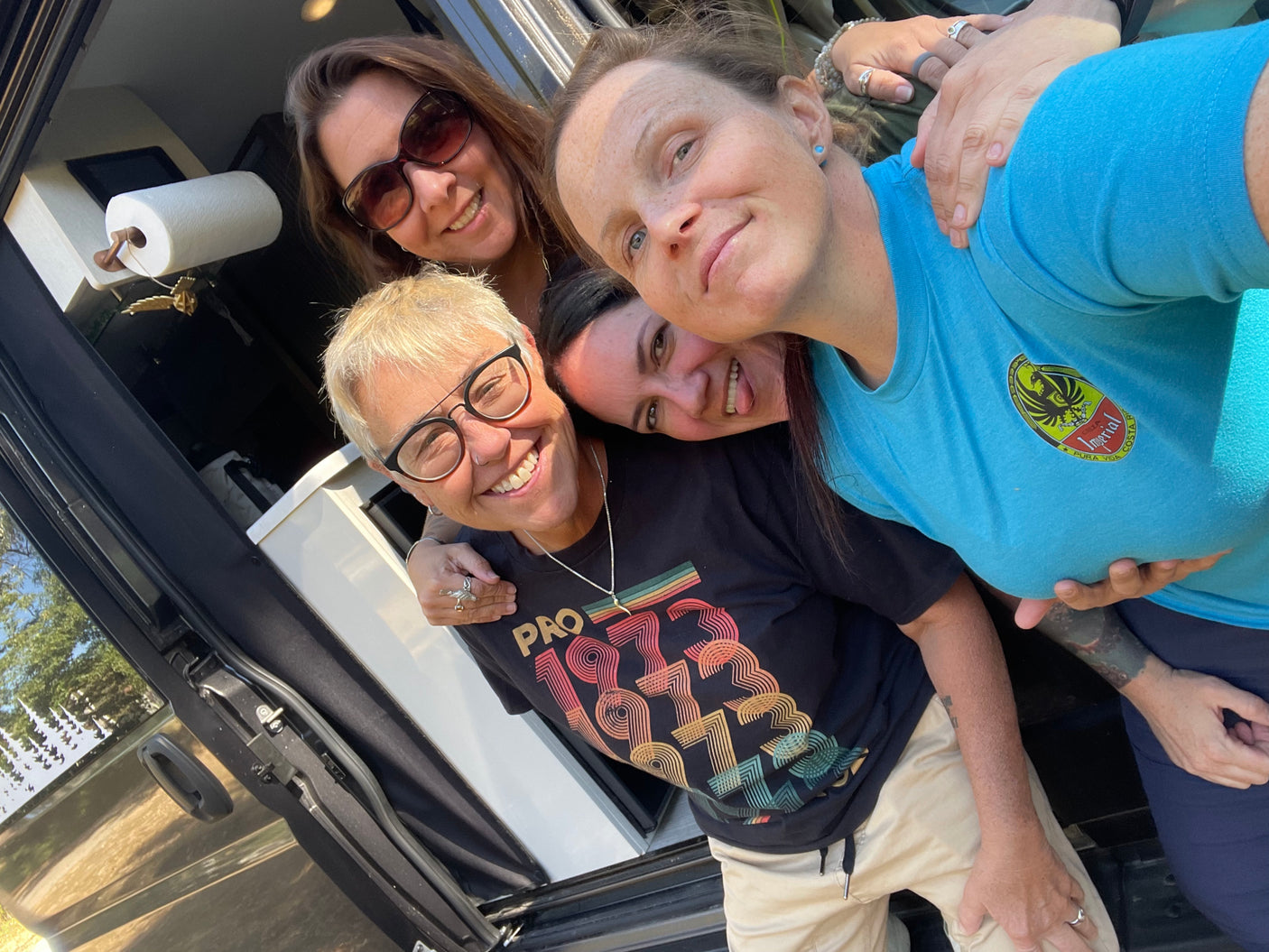Four happy friends smiling inside their RV rental, enjoying a fun road trip.