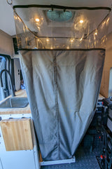 Inside an RV rental: a clear-top shower curtain, bright lights, sink, and compact kitchen setup. Ideal for van life.