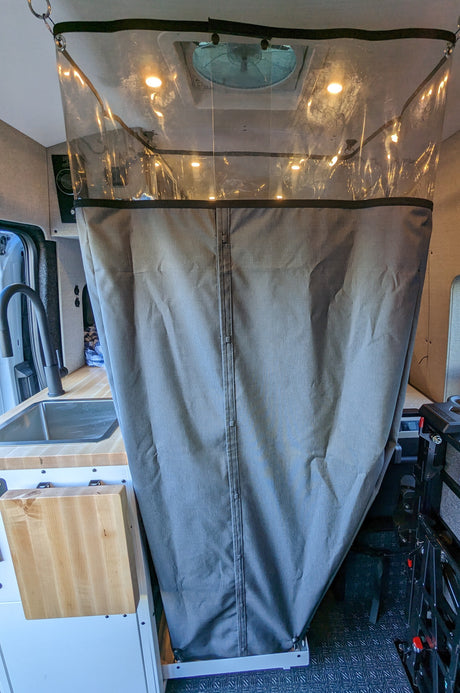 Inside an RV rental: a clear-top shower curtain, bright lights, sink, and compact kitchen setup. Ideal for van life.