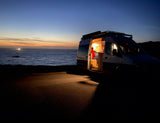 Van life dreams! Cozy interior of an **rv rental** parked by the ocean at sunset. Perfect for road trips.