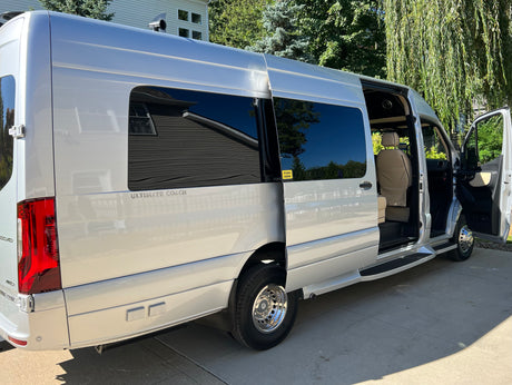 This sleek silver luxury van, ideal for your next rv rental, features an open side door, showcasing its plush interior.