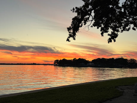 Fiery sunset over a tranquil lake, ideal for RV rental getaways. Enjoy the vibrant sky & water reflections.
