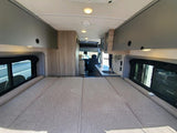 RV rental: Spacious camper van interior with a large bed, kitchen, and overhead storage.