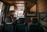 View inside a spacious rv rental van with a full kitchenette, wooden ceiling, and comfortable bunk beds for mobile living.