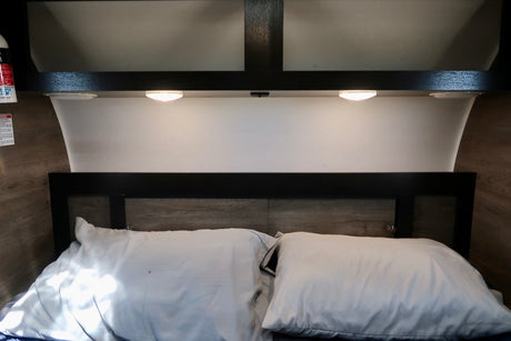 Cozy RV rental bedroom featuring a comfortable bed, two white pillows, and warm ambient lighting.