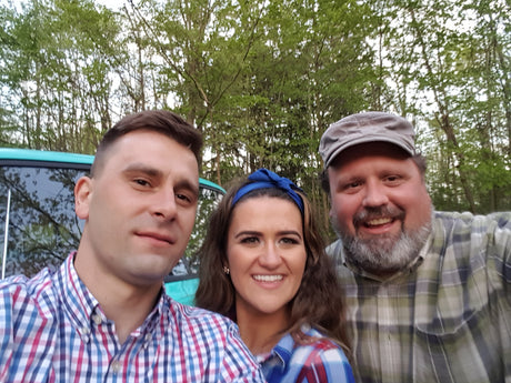 Three smiling travelers enjoying their outdoor RV rental adventure among the trees.
