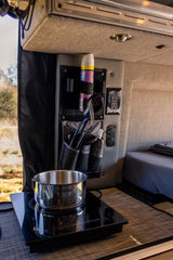 RV rental interior: practical kitchen with an induction cooktop, pot, and organized utensils for easy mobile cooking.