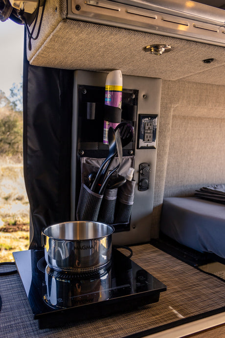 RV rental interior: practical kitchen with an induction cooktop, pot, and organized utensils for easy mobile cooking.