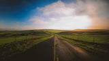 Scenic road winding through green fields under a hazy sky, perfect for an RV rental road trip.