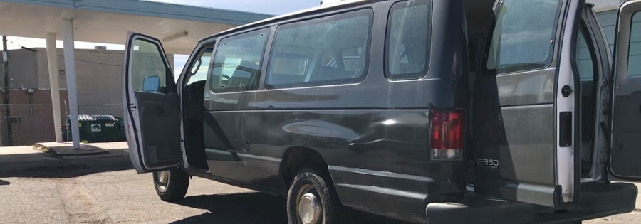 Gray Ford E-350 van with open doors and side dents, ideal for **rv rental** conversions.
