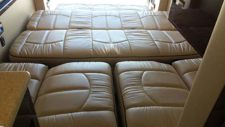 RV rental interior: Beige upholstered cushions forming a convertible bed in a spacious camper. Ideal for travel comfort.