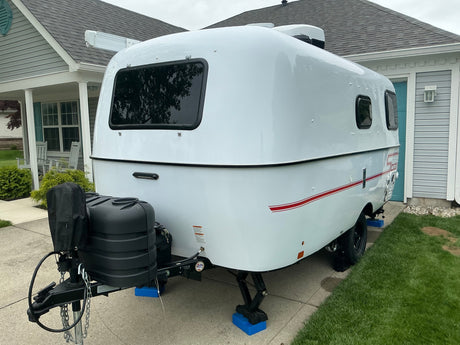  and leveling jacks.|Rear-side view of a white Scamp travel trailer