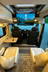 Modern RV rental: cozy interior with comfy seating, TV for entertainment, and a picturesque lake view outside.