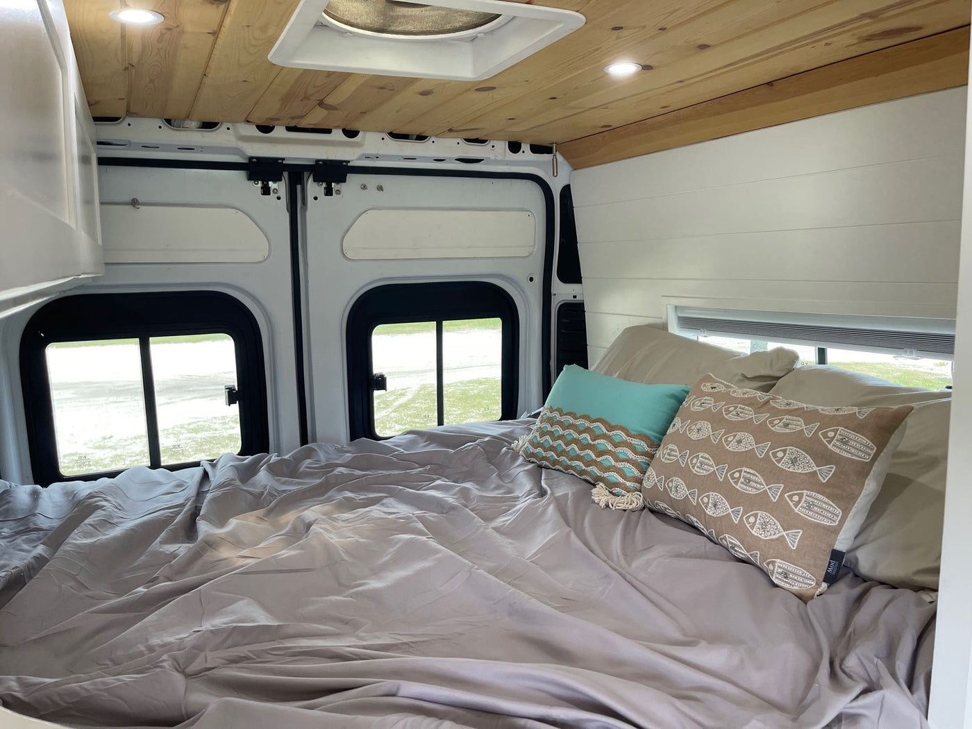  & AC unit under a wood ceiling.|Step into this cozy RV rental! A compact interior offers a functional kitchen with induction cooktop — photo 5