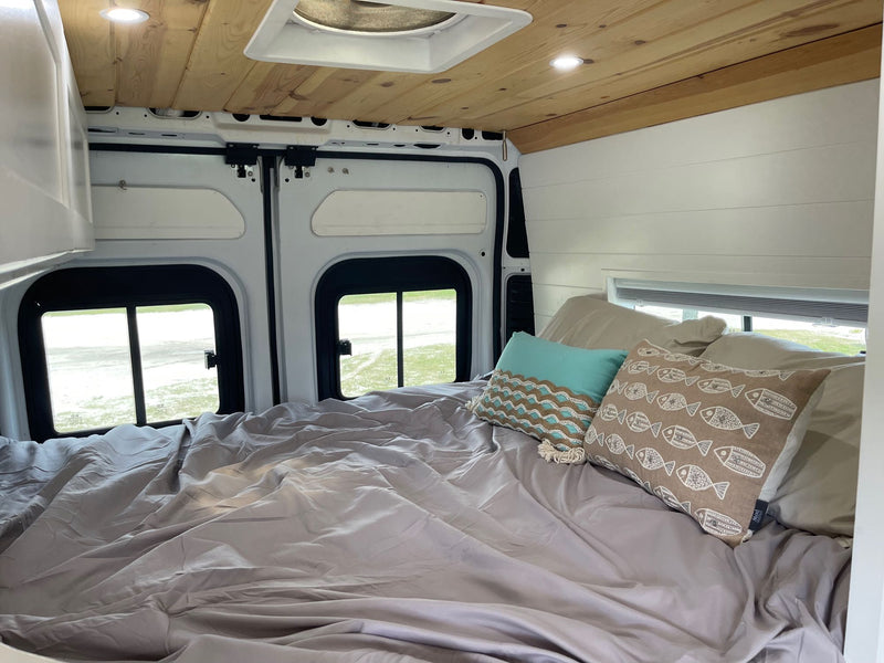  & AC unit under a wood ceiling.|Step into this cozy RV rental! A compact interior offers a functional kitchen with induction cooktop — photo 5
