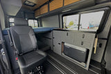 This RV rental showcases a modern camper van interior. Features include an elevated bed, Dometic fridge, modular kitchen & seat.