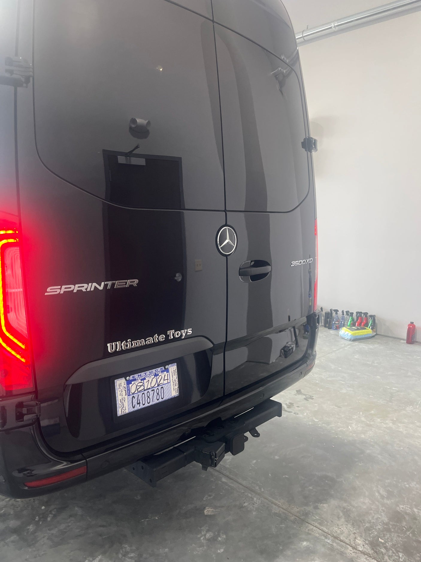 Rear view of a black Mercedes-Benz Sprinter 3500XD luxury van, potentially an RV rental, with a Kentucky temporary tag and tow hitch.
